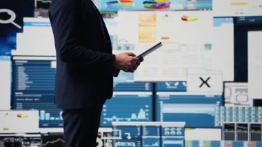 Profesyonel işadamı dijital paneldeki bilgi ve finans grafiklerini analiz ederek tablette bilgi grafikleriyle stratejik planlamayı garanti altına alıyor. Hızlı kurumsal ekonomide liderlik. Kamera B.