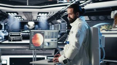 Astronot, uzay istasyonu dışında planlanan operasyonlara girmeden önce gezegen görselleştirmesine bakıyor. Uzay gemisindeki kozmonot gelişmiş mühendislerin gezegen B 'ye inmesiyle çalışıyor.