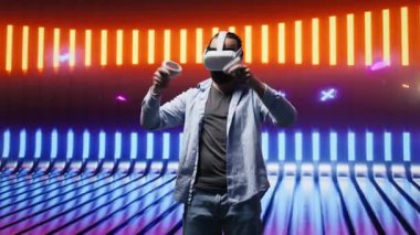 Sanatsal vizyon yoluyla sanal gerçeklik gözlüklerini kullanarak neon ışıklı bir gece sahnesinde yüksek teknolojili VR cihazına sahip genç bir adam. Estetiğin parlak yansımaları, görseller. Kamera B.