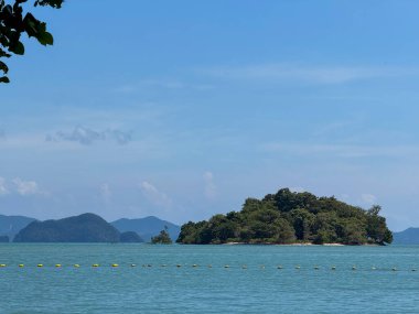 Altın kum ve mavi deniz dalgalarıyla tropik manzara ve sahil, berrak su ve Tayland 'daki küçük orman adaları ile huzurlu bir sahil manzarası.