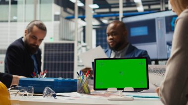 Fotovoltaik fabrikasının hissedarları yatırım stratejisini belirlemek için izole edilmiş ekran tabletindeki pazar eğilimlerini analiz ediyorlar. Yöneticiler modelleme cihazı, genişleyen fabrika üretimi, kamera A verilerine bakıyorlar.