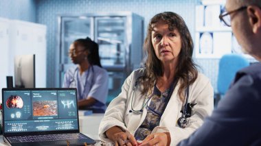 Hastayla konsültasyondaki kıdemli doktor kanser önleme ve erken teşhislerdeki radyografi taramalarını okuyarak kişisel tedavi önerileri sunuyor. Risk faktörleri. Kamera A.