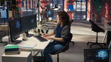 Yapay zeka bulutu için bilgisayar kullanan kadın bilişim geliştiricisi kendini öğrenme algoritmalarıyla hesaplıyor. Ajans sistem mühendisi AI ile birlikte masaüstünde çalışıyor. Kamera A.