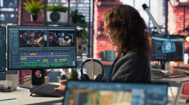 Genç kadın video editörü yaratıcı ajanslarda çift monitörlerle çalışıyor, video görüntülerini düzenliyor ve yaratıcı süreç için renk sınıflandırması yapıyor. İçerik yaratmak için prodüksiyon gönderin. Kamera B.