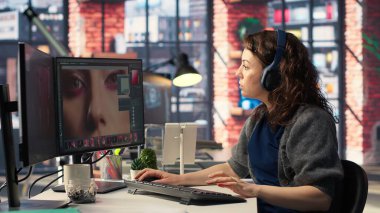 Kadın editör, yaratıcı ofisteki çift ekran masaüstündeki, bilgisayar kurulumundaki fotoğrafları rötuşluyor. Fotoğraf düzenleme üzerine odaklanmış dijital medya profesyoneli için ideal çalışma alanı. Kamera B.