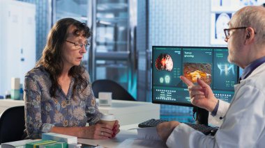 Doktor ve hasta önleyici tıp ve kanser farkındalığı stratejileri üzerine odaklanan bir röntgen ve MRI taraması hakkında tartıştılar. Bir kadını kemoterapi seçenekleri ve önleyici bakım konusunda eğitmek. Kamera B.