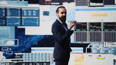 İcra kurulu başkanı, büyük veri analizi ve ekonomik tahminleri koordine etmek için telefon görüşmesi yapıyor. Gösterge panelinde bilgi grafikleri ve şirket performansına rehberlik etmek için modern ölçümler paylaşılıyor. Kamera B.