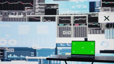 Bilgi grafikleri raporlarının yanındaki boş masanın üzerinde boş ekran bulunan dizüstü bilgisayar, finans grafikleri ve yeni yatırım ve karar verme araçları sergileniyor. İş büyümesi. Kamera B.