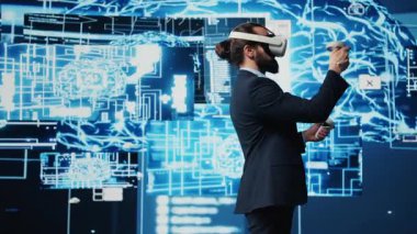 VR gözlükleri ve yapay zeka beyni kullanan iş bilişim uzmanı, makine öğrenimi için arayüz içinde veri görselleştirme sibernetiği üzerinde çalışıyor. Yenilik için yüksek teknoloji aleti. Kamera B.