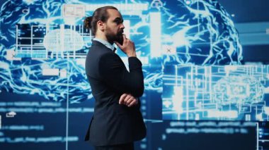 Genç işadamı torpido gözündeki yapay zeka sinir ağlarını inceleyerek, kodlama, analitik ve stratejik gelişim için yüksek teknolojili otomasyon araçları kullanıyor. Kamera A.