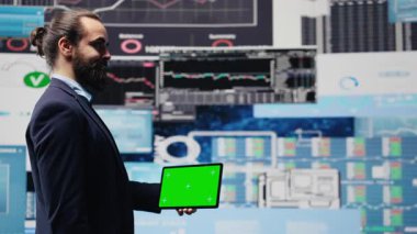 Erkek yönetici, dijital çalışma alanındaki içgörü ve analizlerle yeni büyüme stratejilerini keşfetmek için yeşil ekranlı telefonu kullanır. Modern iş zekasını ve verimliliğini temsil ediyor. Kamera B.