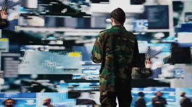 Silahlı kuvvetler subayı, savaş planlaması için bilgi toplamak amacıyla İHA ve uydu görüntülerini izliyor. Görev kontrol ve siber savunma yoluyla küresel operasyonları güvence altına almak. Kamera B.