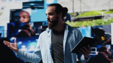 Erkek havalı bilişim uzmanı elleri serbest mikrofonla canlı bir kongreye ev sahipliği yapıyor, sahneden izleyicileri sosyal medya erişimi ve dijital etkileşimi tartışmak üzere bir araya getiriyor. İletişim. Kamera A.