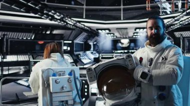 Koruyucu miğfer tutan gülümseyen astronot portresi uzayda insan genleşmesi yapıyor. Yıldız gemisindeki neşeli adam uzun vadede insanlığın kurtuluşunu destekleyen keşif gezisine hazırlanıyor.