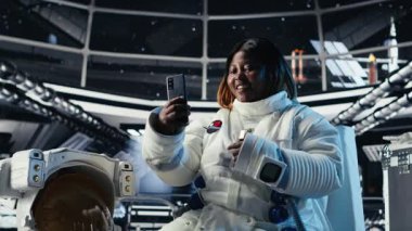 Neşeli bayan astronot, galaktik görev sırasında abonelerle konuşurken akıllı telefonlu selfie videosu kaydediyor. Yıldız gemisindeki neşeli Afrikalı Amerikalı kadın takipçiler için içerik kaydediyor, kamera B