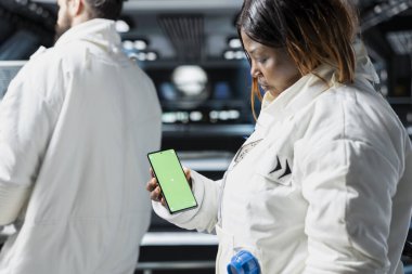 Bilim adamları uzay yolculuğu sırasında gelişmiş uzay gemisinde krom anahtar akıllı telefon kullanarak görsel veri testleri yapıyorlar. Kozmonotlar, analiz için izole ekran telefonuna güvenerek yörünge deneyleri gerçekleştirirler.