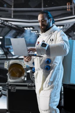 Astronot araştırmacısı görev parametrelerini doğrulamak için dizüstü bilgisayar kullanıyor ve gemide araştırma yapıyor. Uzay gemisinde kozmonot teçhizatı takan bilim adamı not defteri aygıtı kullanarak uçuş günlüğünü güncelliyor