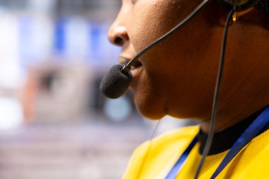 Akıllı imalat fabrikasındaki Afrikalı Amerikalı teknisyen el kulaklığı takıyor, dijital kontrollü otomatik üretim sistemini, robotik kolları ve endüstriyel otomasyonu denetliyor..