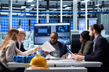 Güneş panelleri fabrika hissedarları rekabet analizi yapıyor, dosyalara bakıyor. Fotovoltaik fabrikası hissedarları potansiyel yatırım fırsatları üzerine araştırma yapıyor, belgeleri okuyorlar