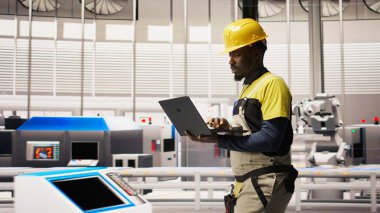 Otomatik çevre dostu fabrikada fotovoltaik montaj sistemlerinin korunması için dizüstü bilgisayar kullanarak güneş paneli üretim hatlarını inceleyen mühendis, kamera A