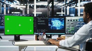 Parapleji yapan veri merkezi mühendisi yeşil ekrandaki yapay zeka öğrenme algoritmalarını kullanarak veri tabanlarını analiz ediyor. Yapay zeka nöro ağları kullanarak Chroma Key PC 'de tekerlekli sandalyedeki sunucu odası çalışanı, kamera B