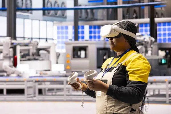 Afrikalı Amerikalı mühendis endüstriyel eğitim sırasında sanal gerçeklik teknolojisiyle etkileşime geçiyor. Sanayi 4.0 deposunda VR kulaklıklı bir fabrika müdürü ürün simülasyonuyla uğraşıyor..