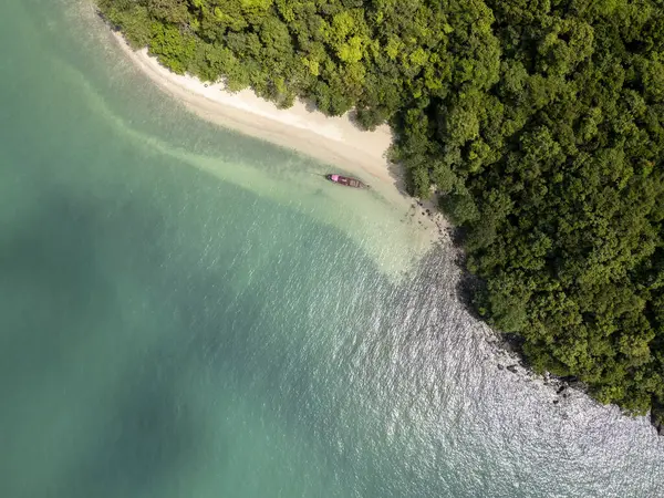 Sahilde yelkenli teknesi olan tropikal kumlu bir sahil manzarası, altın kumu olan güzel bir plaj manzarası. Kıyıdaki mavi sularda yumuşak kum ve çarpıcı bir deniz manzarası olan bir tekne yanaştı..