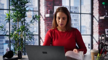 Olgun bir kadının şık çatı katında dizüstü bilgisayarı üzerinde odaklanması, serbest iş ve uzak sorumlulukları yönetirken internete bağlanması. Ev ofisinde web taraması. Kamera B.