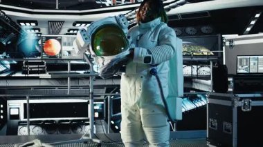 Yüksek teknolojili uzay aracının içinde miğfer tutan neşeli astronot portresi, rutin görev kontrolü sırasında ekipman çantası. Yıldızgemisindeki neşeli kadın Mars verilerini gösteren monitörün yanında duruyor.