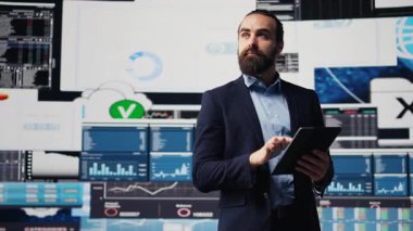 Yeni bir büyüme stratejisi için gösterge panelindeki aylık performans ölçümlerini yansıtan iş uzmanı, mali durumu ve şirketin raporlarını analiz ediyor. Dijital aletler. Kamera B.