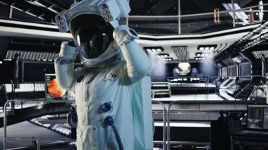 Neşeli astronot yüksek teknolojili uzay gemisinin içine miğfer takıyor, gezegen görevi için ekipman hazırlıyor. Yıldızgemisindeki neşeli Afrikalı Amerikalı kadın Mars verilerini gösteren monitörün yanında duruyor.