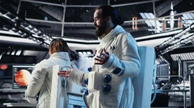 Astronot dalgaları, Dünya Komuta Merkezi ile video görüşmesi sırasında uzay gemisinde görev güncellemesini paylaşırken el ele veriyor. Kozmonot, yer merkezi ve kamera B arasındaki iletişim sırasında araştırmacıları selamladı