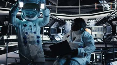 Uzay istasyonunun dışına çıkmadan önce laptopta veri analizi yapan astronot ekibi. Gezegen A 'ya indikten sonra görev parametrelerini doğrulayan takım çalışması.