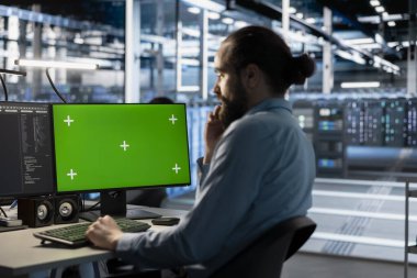 Veri merkezinde sunucu teknolojisini güncellemek için yeşil ekran modelleme bilgisayarı kullanan teknisyen yazılım araçları kullanarak ekipmanları yapılandırıyor. Sunucu odası çalışanı krom anahtar PC üzerindeki donanım analizlerini gözden geçiriyor