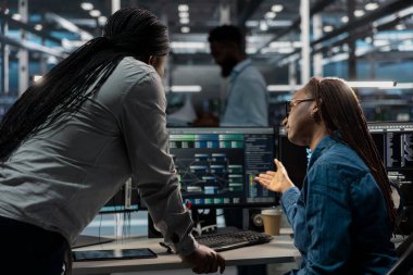 Veri merkezi yazılım geliştiricileri PC kullanarak yapay zeka sinirsel ağlarını görselleştirdiler. Sunucu odası lideri ve bilgisayar monitörüne bakan ve yapay zeka sistemlerini denetlemek için birlikte çalışan bir işçi.