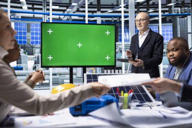 Endüstriyel fabrika yöneticileri ürün yeniliklerini kroma anahtar ekranı kullanarak sergiliyorlar. Müşteriler için satış sunumu yapan fabrika işadamları, izole ekran monitörü kullanarak güneş paneli çözümleri gösteriyorlar