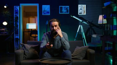 Televizyonda spor maçı izleyen şaşkın taraftar, ikna edici olmayan takım performansına şaşırdı. Futbol müsabakasına bakan bir adam, oyuncunun kolayca kaçırdığı için şaşkın, kamera B, yakın plan.