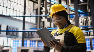 Akıllı fabrikada çalışan iyimser bir profesyonel robot üretim hatlarını denetliyor ve kalite kontrolü sağlıyor. Endüstri 4.0 bitki uzmanı otomatik taşıma sistemlerini not defteri, kamera A kullanarak izliyor