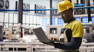 Akıllı fabrikadaki mühendis dizüstü bilgisayar yazılımı kullanarak IoT sensör verilerini analiz ediyor. Fotovoltaik sistemlerin işlevsel güvenilirliğini yöneten sanayi 4.0 fabrika işçisi not defteri, kamera A