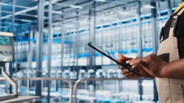 Akıllı fabrika uzmanı otomatik sistemleri test etmek ve güvenilirliği sağlamak için dijital cihaz uygulaması kullanıyor. İşçi, dar boğazları tanımlamak için tablet kullanır ve sensör verilerine ve kamera görüntülerine dayanarak ekipmanları optimize eder.