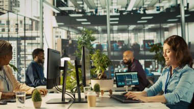 Finansal grafikleri incelerken neşeli iş arkadaşları coşkulu ofiste eğleniyorlar. Neşeli meslektaşlar çalışırken şakalarını paylaşıyor, veri eğilimlerine ve stratejik görüşlere bakıyor, kamera B