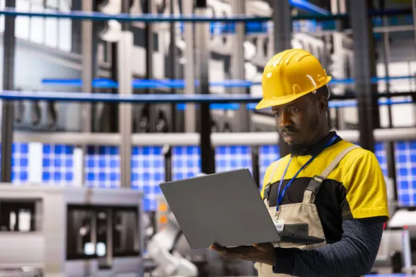 Akıllı üretim tesisinde, siyah adam robotları ve otomasyon sistemlerini denetlemek için dizüstü bilgisayar kullanır ve en iyi performansı sağlar. Teknisyen fabrikada sanayi 4.0 yazılımının kalite kontrolünü yürütüyor..