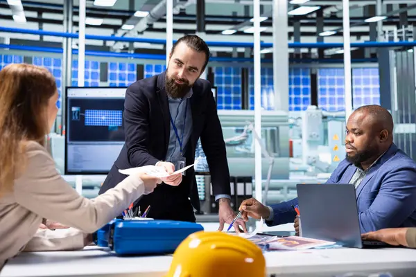 Fabrika müdürü, anlaşmayı imzalamadan önce mali tabloları inceleyen yatırımcılara evrak dosyaları veriyor. Endüstriyel fabrika yöneticisi hissedarlara uyum kayıtları sunuyor