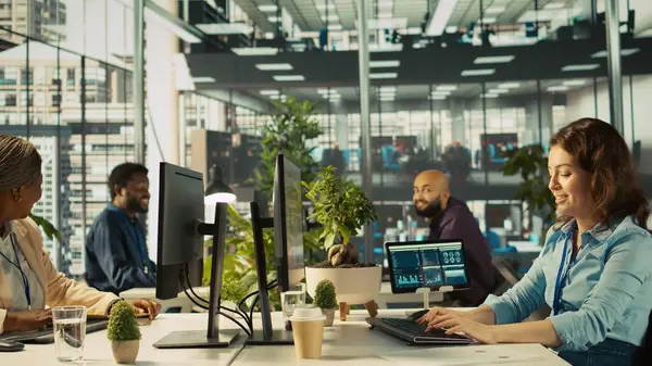 Finansal grafikleri incelerken neşeli iş arkadaşları coşkulu ofiste eğleniyorlar. Neşeli meslektaşlar çalışırken şakalarını paylaşıyor, veri eğilimlerine ve stratejik görüşlere bakıyor, kamera B