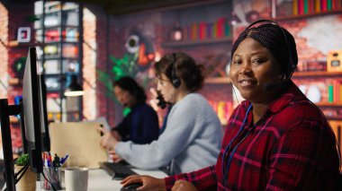 Gülümseyen çağrı merkezi ajanı müşterilere dijital iletişim kanallarından yardım ediyor. Müşteri desteği çalışanı bilgisayarla müşteriyle canlı sohbet yapıyor, kamera B