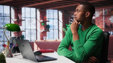 Siyahi serbest çalışan, kâr ve ulaşımı arttırmak için yeni çözümler düşünüyor, finansal büyüme için fikir üretmek için birden fazla iş yapıyor. Genç uzaktan kumandalı işçi, yaratıcılığını başarı için kullanır. Kamera B.