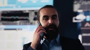 İş adamı dijital analitik ve şirket görüşünü değerlendirmek için bir akıllı telefon görüşmesine cevap veriyor. Mali veriler ve eğilim raporlarıyla çevrelenmiş olarak, liderlik hedefleri ve projeksiyonları belirliyor. Kamera A.