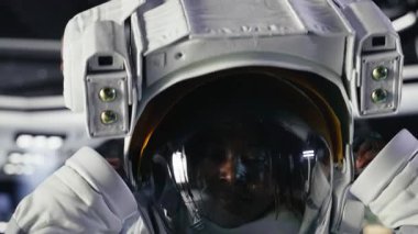 Neşeli astronot yüksek teknolojili uzay gemisinin içine miğfer takıyor, gezegen görevi için ekipman hazırlıyor. Yıldızgemisindeki neşeli Afrikalı Amerikalı kadın Mars verilerini gösteren monitörün yanında duruyor.