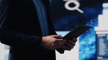 Profesyonel işadamı dijital paneldeki bilgi ve finans grafiklerini analiz ederek tablette bilgi grafikleriyle stratejik planlamayı garanti altına alıyor. Hızlı kurumsal ekonomide liderlik. Kamera A.