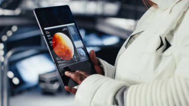 Fütürist uzay gemisinin içindeki astronot rutin görev kontrolü sırasında Kızıl Gezegen yolculuk analizlerini kontrol ediyor. Uzay istasyonu kozmonotu, Mars keşif ölçümlerini gösteren monitörün yanında duruyor.